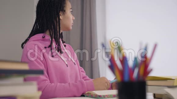 旁边的美丽年轻的非裔美国女孩坐在桌子旁仔细听教授的话肖像视频的预览图