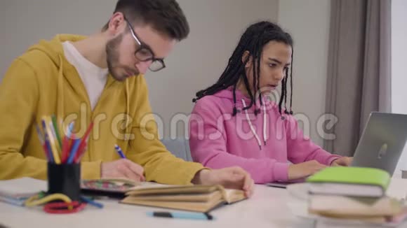 穿着紧身衣的非裔美国女孩合上笔记本电脑双手交叉着正如她的男性白种人在眼镜上滚动的伴侣视频的预览图