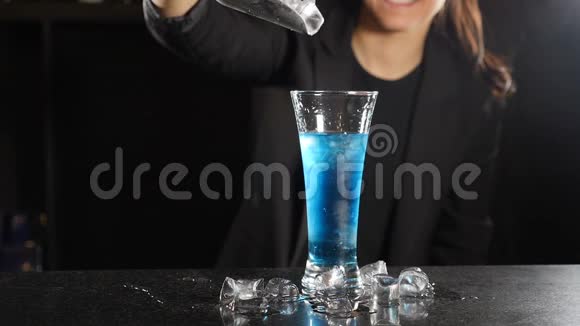 缓慢的运动镜头冰块掉进充满蓝色液体的玻璃中溅出碎片快关门女调酒师视频的预览图