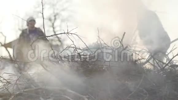 一群干树枝在前台燃烧这是一对高种高加索农民在后台控制着火势视频的预览图
