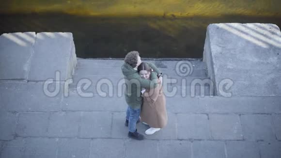 俯视年轻的高加索男人和女人在河岸上拥抱在户外浪漫约会的快乐情侣视频的预览图