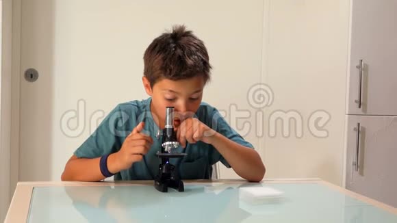 好奇的黑发少年正透过显微镜看着视频的预览图