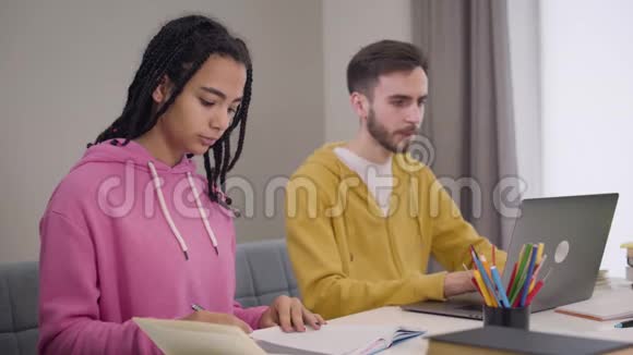 侧面看模糊的白种人男孩使用笔记本电脑并征求美丽的非裔美国女孩的建议视频的预览图