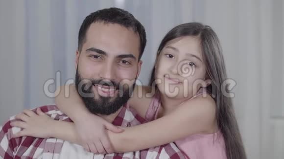特写照片中快乐的中东父女对着镜头微笑棕色眼睛的男人和小女孩视频的预览图