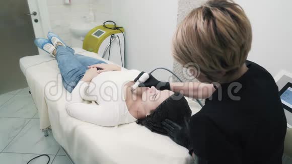 侧视美容师在诊所对女性领口做保湿手术视频的预览图