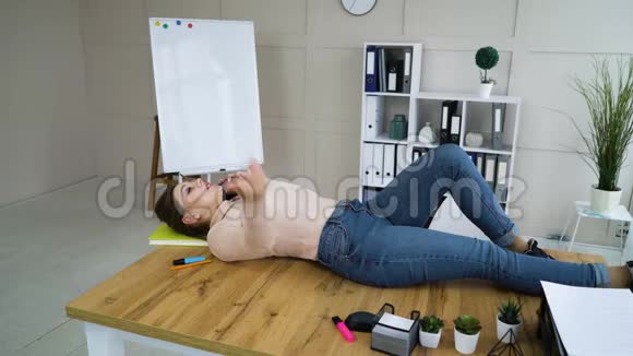 女企业家躺在桌子上在办公室打电话视频的预览图