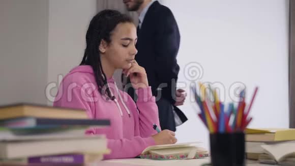 年轻的白种人男教师来到非裔美国学生翻阅她的笔记很害羞的女孩视频的预览图