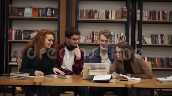 一群年轻的学生在图书馆一起用笔记本电脑讲解课程积极讨论视频的预览图