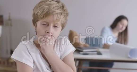 疲惫的金发白种人男孩的肖像灰色的眼睛打哈欠和看相机他年轻的母亲坐在视频的预览图