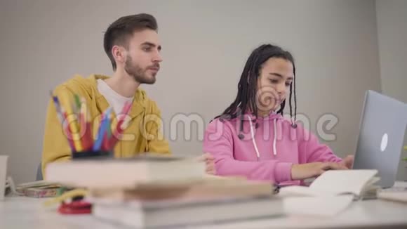 快乐的白人男孩看着非裔美国女孩在键盘上打字开朗的女生关闭笔记本电脑视频的预览图