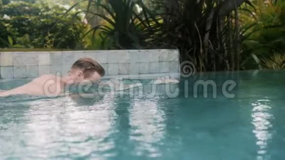 壮汉在流行的热带度假胜地的游泳池里游泳视频的预览图