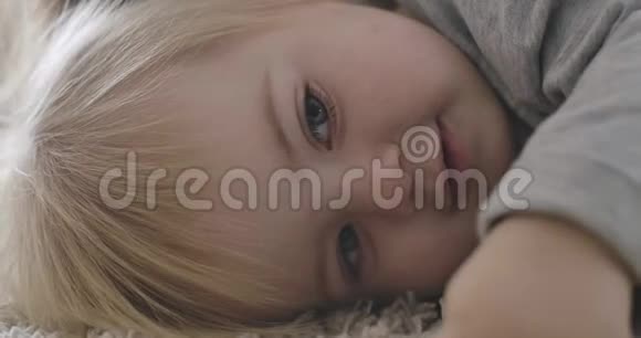 迷人的白种人女婴的特写脸灰色的眼睛和金发躺在母亲手上美丽的肖像视频的预览图