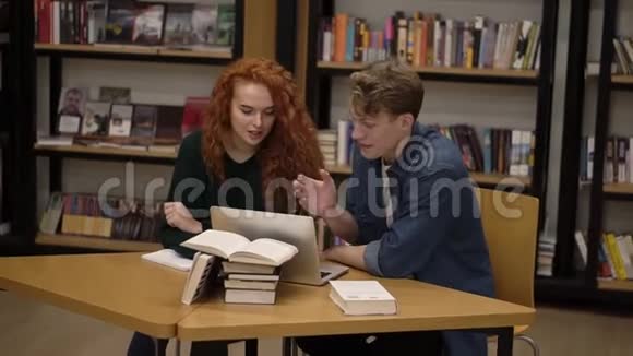 年轻的男女学生使用笔记本电脑交谈解释课程一起在图书馆学习积极主动视频的预览图