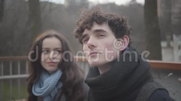 一个年轻的白种人卷发男子抬头微笑着女朋友把头靠在他的肩膀上视频的预览图