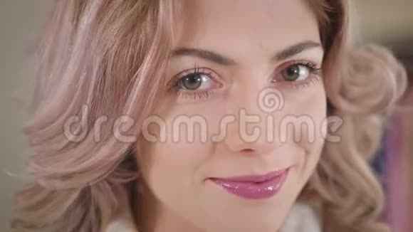美丽的白种人女人的特写脸有着淡褐色的眼睛和卷曲的头发看着相机微笑着年轻快乐视频的预览图