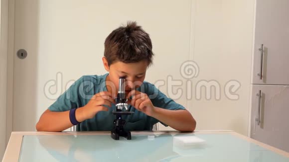 严肃的黑眼睛男孩正在调节显微镜视频的预览图