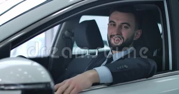 在驾驶座上摆在车上的白人年轻人满意特写肖像积极的帅哥买新的视频的预览图