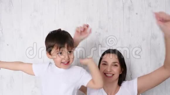 母亲和儿子在一张白色的床上快乐地跳舞视频的预览图