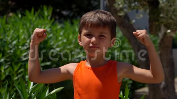 穿橙色衬衫的快乐男孩展示了肌肉视频的预览图