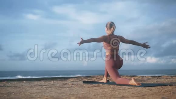 女人做瑜伽运动早上在海滩的垫子上做伸展运动视频的预览图