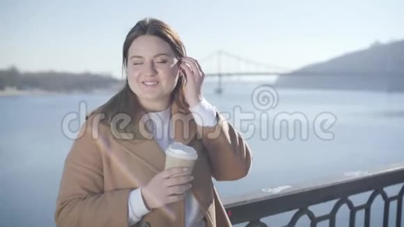 年轻胖乎乎的白种人黑发女孩的肖像棕色的眼睛站在河岸上的阳光积极的妇女视频的预览图