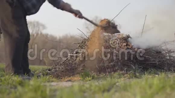 成熟的白人农民用铲子把干燥的叶子和树枝扔到户外的火里环境问题反视频的预览图
