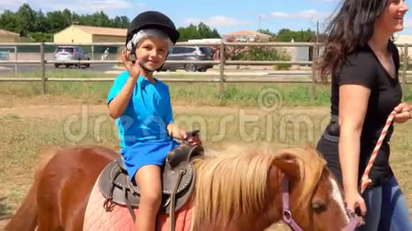 小男孩骑着一匹小马挥动他的手露出一个大拇指视频的预览图
