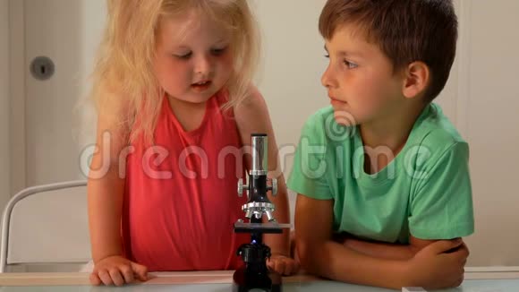 男孩帮助可爱的女孩透过显微镜看视频的预览图