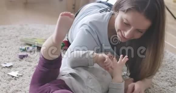 年轻的白种人母亲躺在柔软的地毯上用小女孩触摸她的手指Brunette妇女视频的预览图