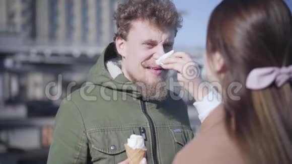 无法辨认的黑发女人用冰激凌清洗男友的鼻子乐观的年轻人微笑着看着视频的预览图