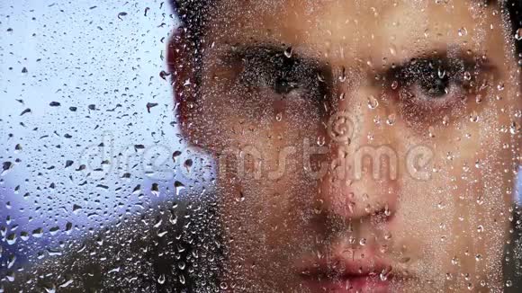 一场雨后白种人的外表透过潮湿的窗户看着特写镜头视频的预览图