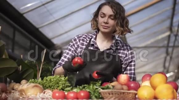 站在农场市场上戴着黑色手套摆放有机食品的美丽微笑的女农低视角视频的预览图
