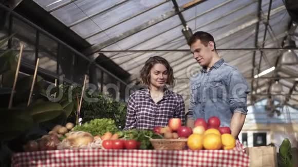 美丽的白种人农民画像男人和女人在农场市场上放围裙和手套销售有机食品视频的预览图