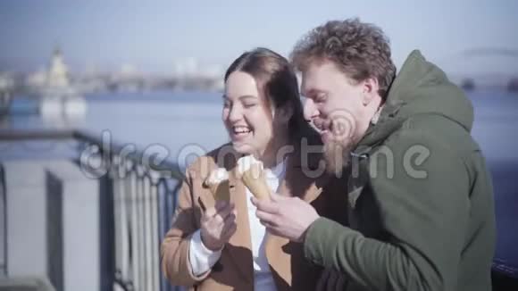 快乐的年轻夫妇站在桥上平静的河底吃冰淇淋积极的白人男孩视频的预览图