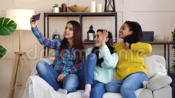 快乐的女孩坐在家里用智能手机现场直播视频的预览图