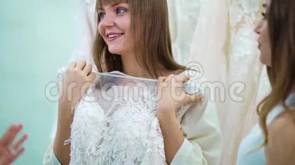 微笑新娘与伴娘尝试豪华婚纱在沙龙视频的预览图