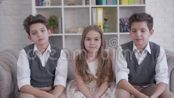 三个积极的高加索儿童坐在沙发上竖起大拇指的肖像双胞胎兄弟和小可爱视频的预览图