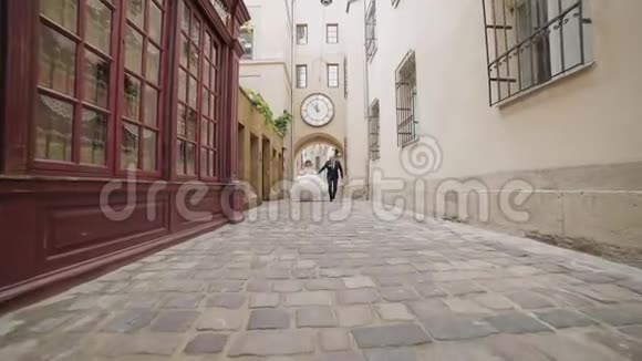 新婚夫妇在老城的中心奔跑新郎新娘婚礼视频的预览图
