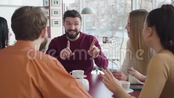 一幅英俊的白种人白种人在咖啡馆里和一群朋友交谈微笑着的肖像积极的年轻人视频的预览图