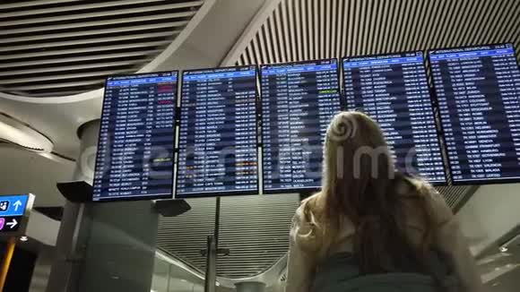女在国际机场看航班信息板视频的预览图