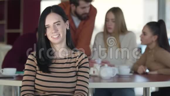 快乐的成年白种人女孩的肖像黑发看着相机微笑年轻女子在咖啡馆摆姿势视频的预览图