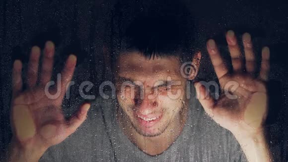 雨后一个白人靠在潮湿的窗户上哭着很伤心患有抑郁症全球气氛视频的预览图
