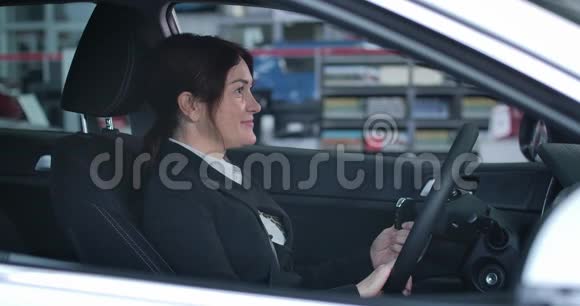 自信的白人女性坐在司机新车上的座位上一边看着相机一边微笑视频的预览图