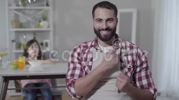 中东男人穿着围裙手握钢包像一个模糊的小女孩坐在桌旁视频的预览图