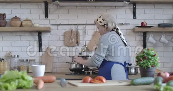 严肃的中年白种人女人在炉子上做饭准备高级家庭主妇的背面肖像视频的预览图