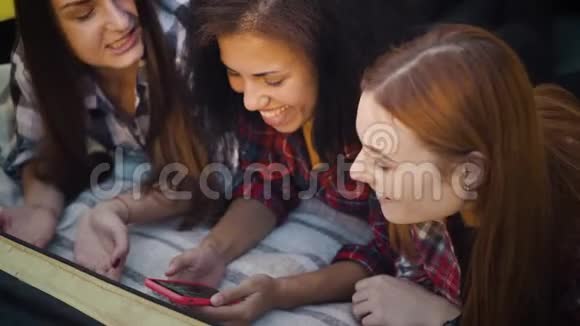 漂亮的女孩躺在毯子上浏览社交媒体视频的预览图