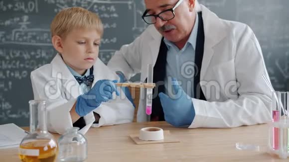 好奇的孩子拿着玻璃管加热物质在实验室观察与老师的反应视频的预览图