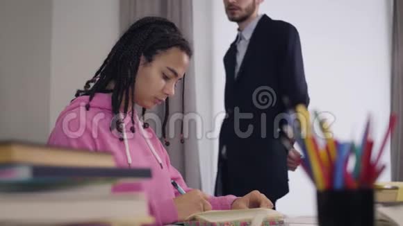 侧视肖像画美丽的非裔美国女孩写下年轻的白种人教师穿着西装走在视频的预览图