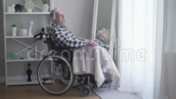 侧面看成熟的白种人白发男子坐在轮椅上思考孤独的老人独自度过一天视频的预览图