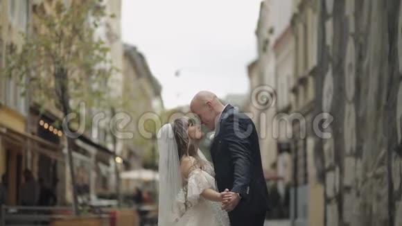老镇中心的新婚夫妇新郎新娘接吻婚礼视频的预览图
